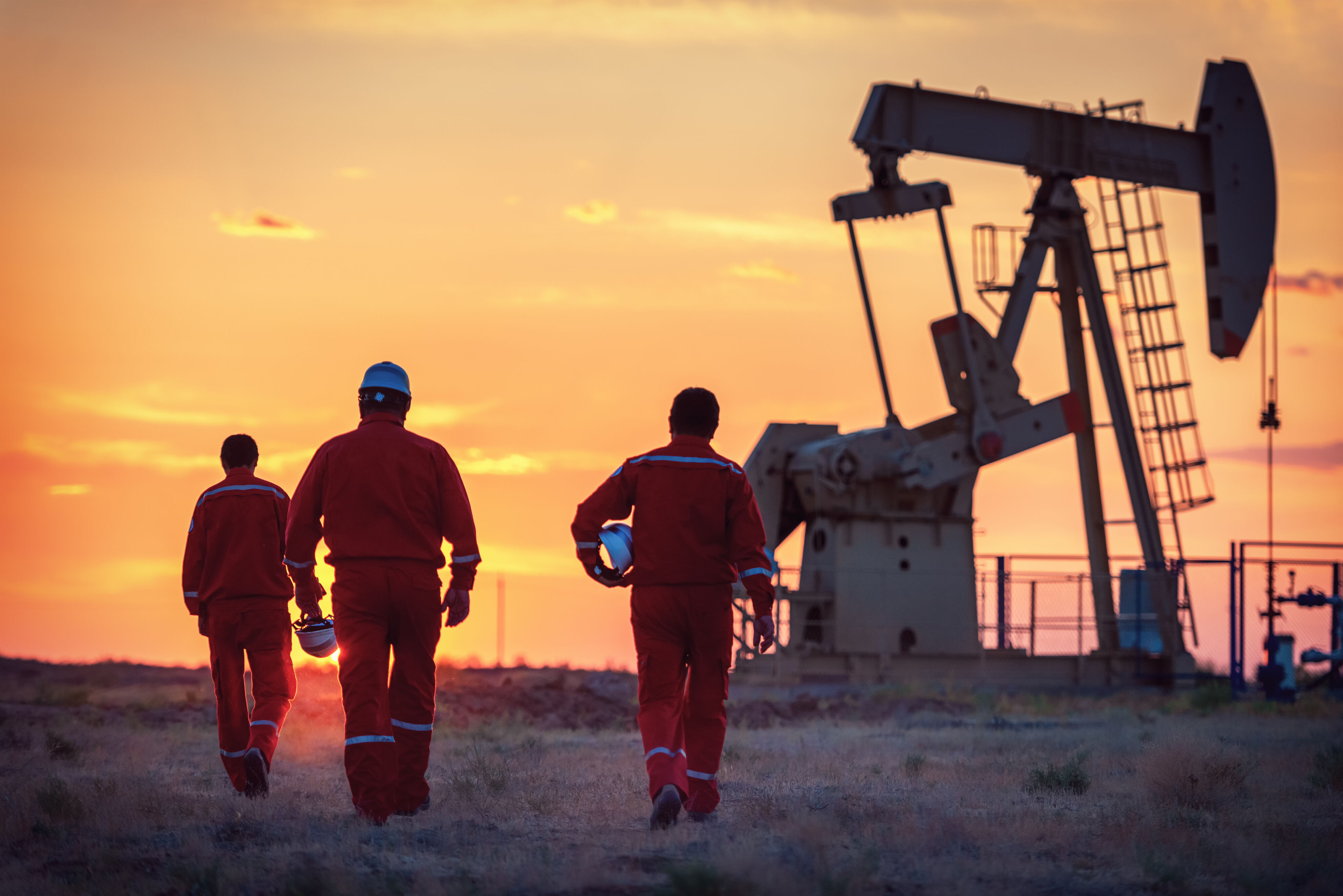 Three oil workers at oil drill.